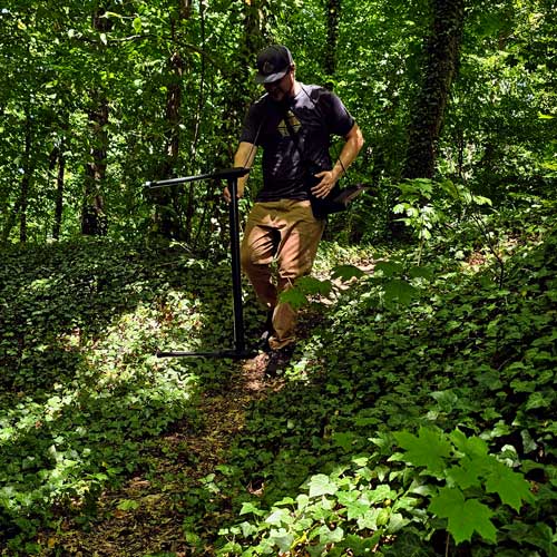 Man walking through a forest with an OKM detector